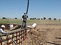 Pump operator uses a wireless remote to guide the concrete output tube into the forms.